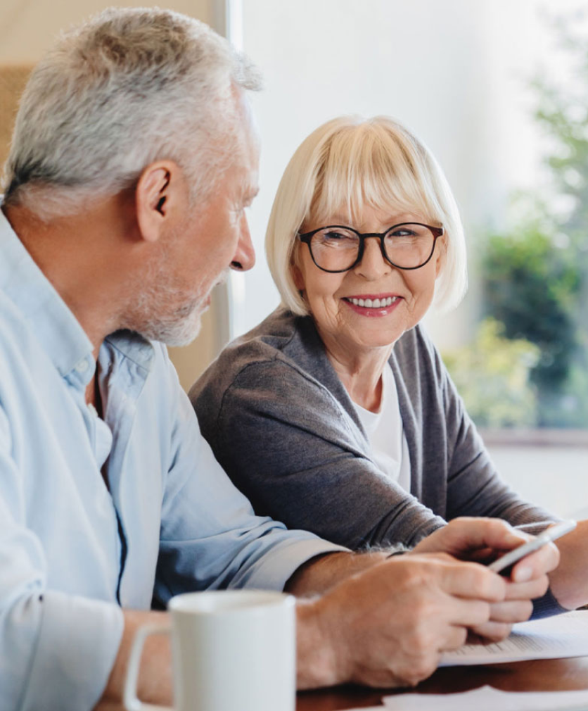 Senior couple smiling and looking over medical paperwork