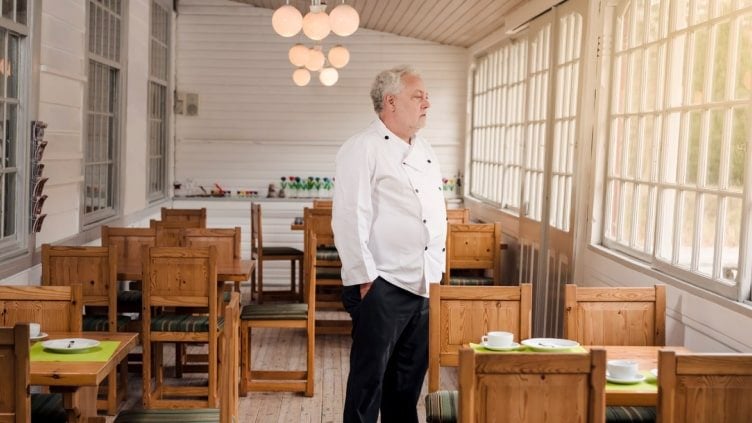 older man standing in empty restaurant