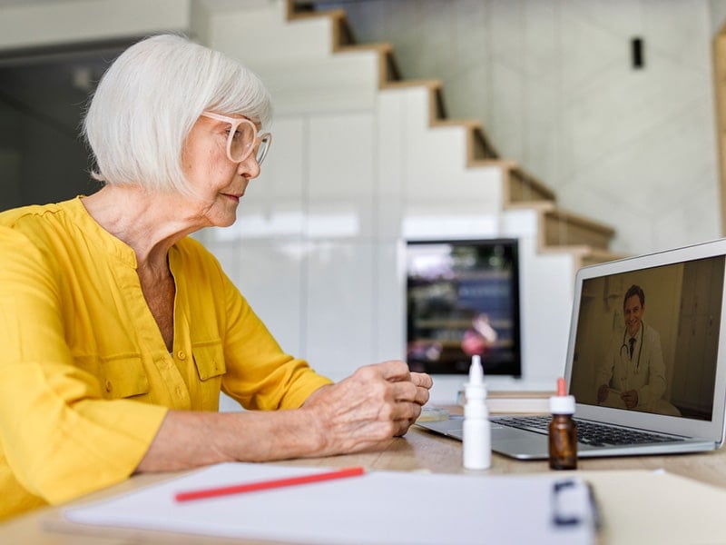 older woman using telehealth service and talking to doctor through laptop