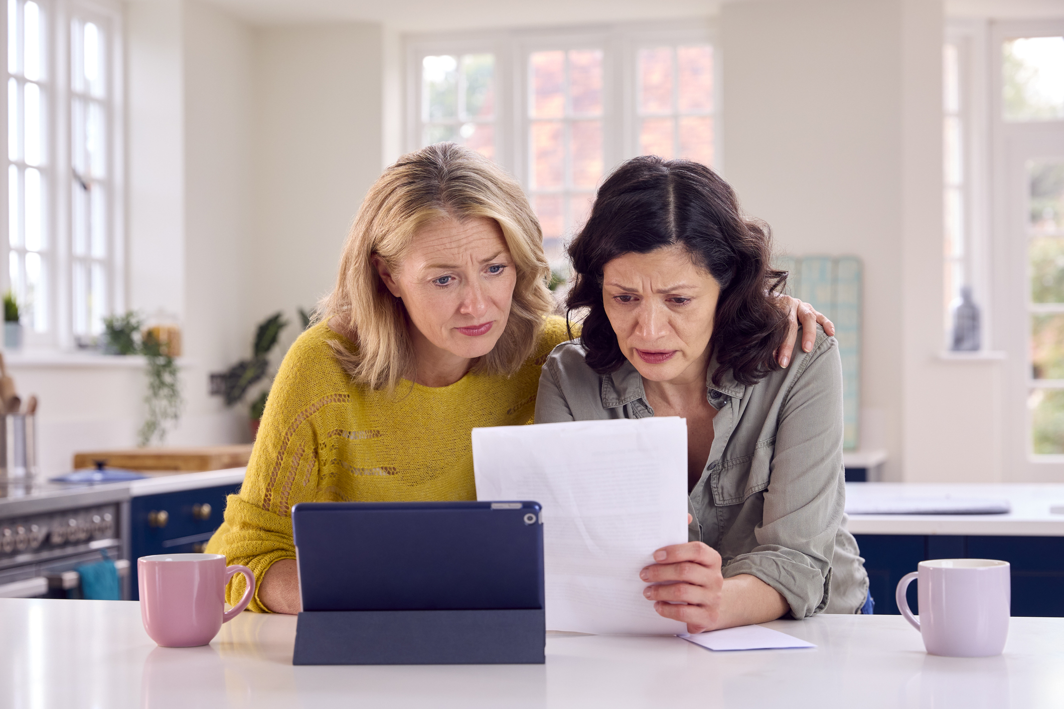 Mature Female Same Sex Couple Using Digital Tablet At Home To Check Domestic Finances