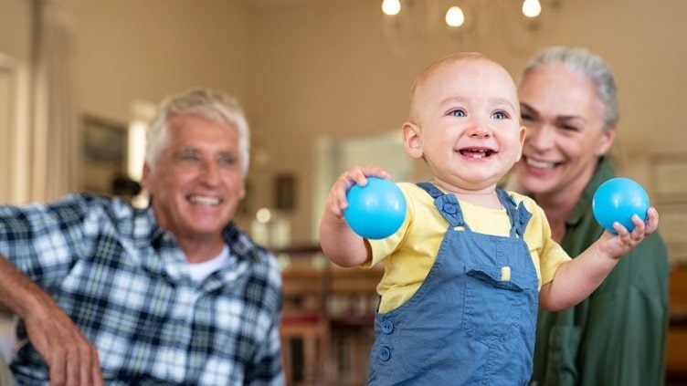 Grandparents watching toddler walking with toys