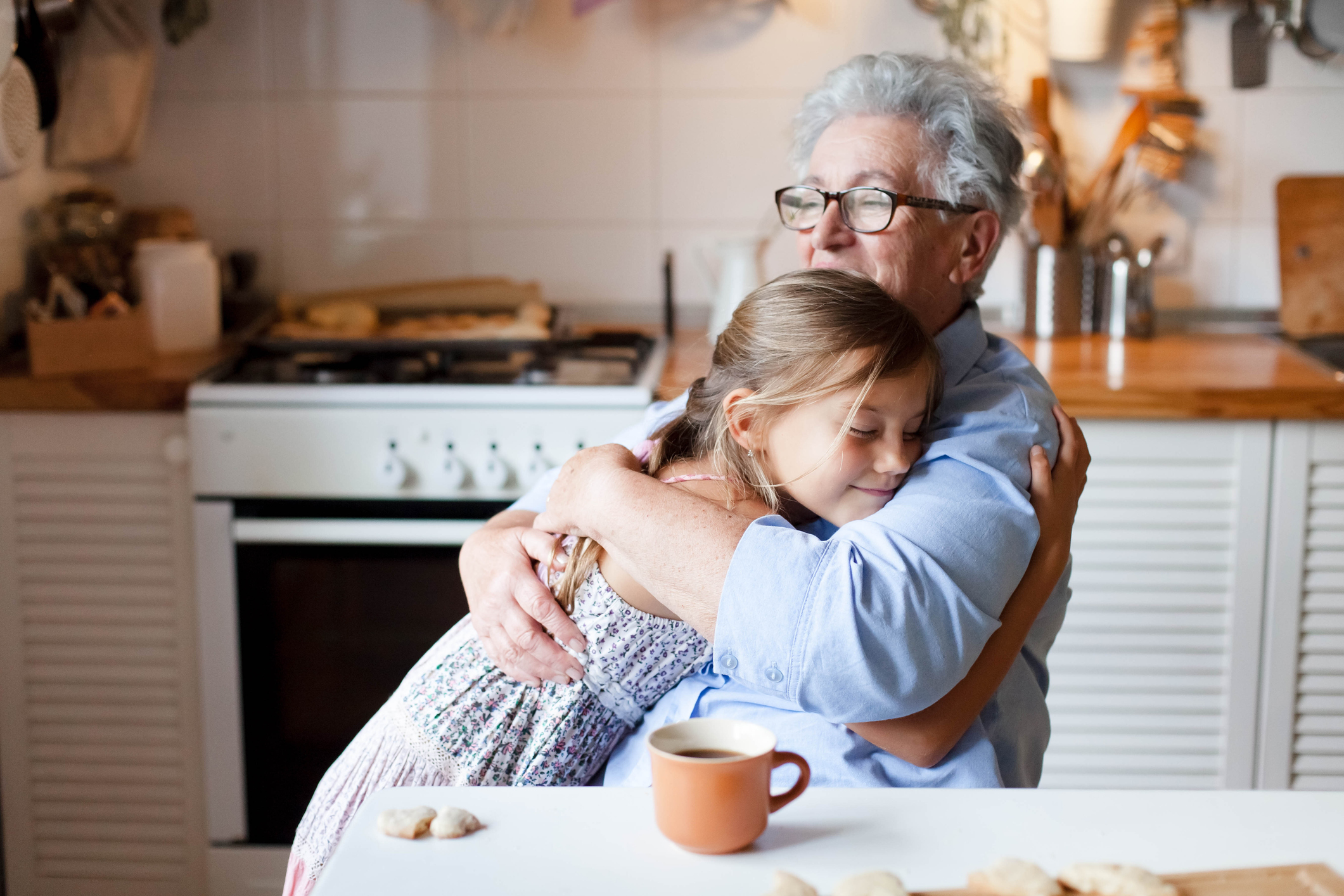 A grandmother gives her granddaughter a warm embrace in her kitchen