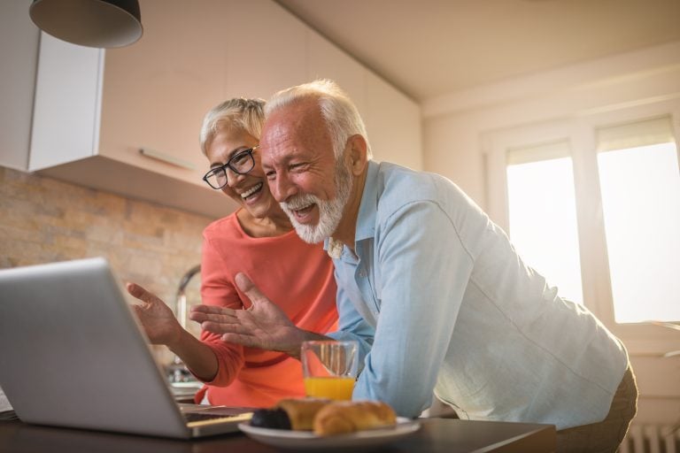 Happy senior couple using a laptop in their kitchen