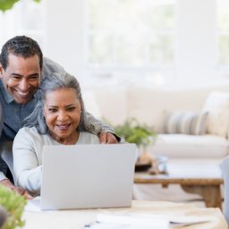 Husband looks over wife's shoulder at laptop
