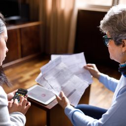 young woman with calculator looking over paperwork with an older women