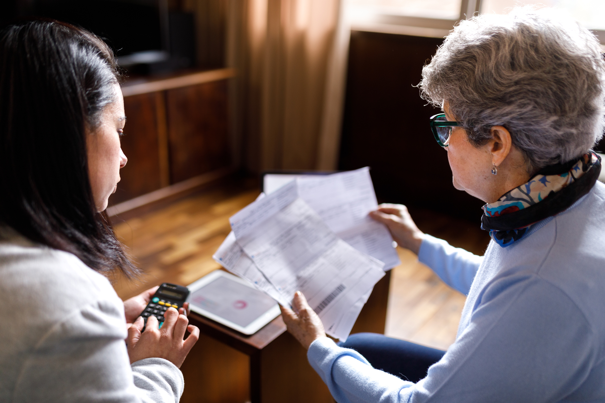 young woman with calculator looking over paperwork with an older women