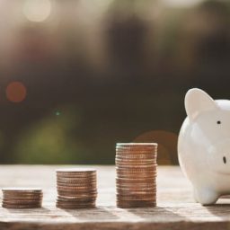 piggy bank on table with coins alongside