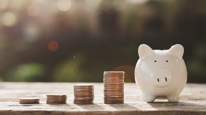 piggy bank on table with coins alongside