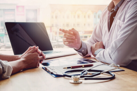 Patient and doctor talking with computer on desk