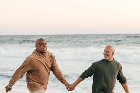 Two men at the beach, embracing each other and watching the sunset