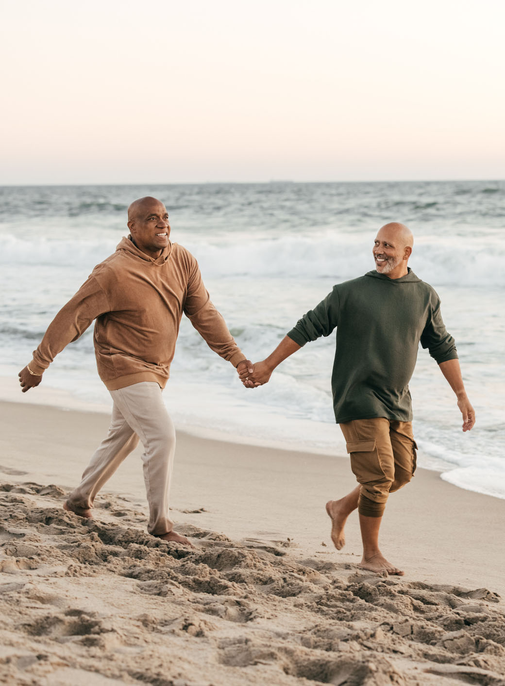 Two men at the beach, embracing each other and watching the sunset