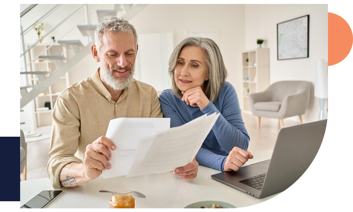 Middle aged couple reading paper bills calculating finances using laptop at home