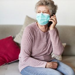 Older woman in mask using cell phone