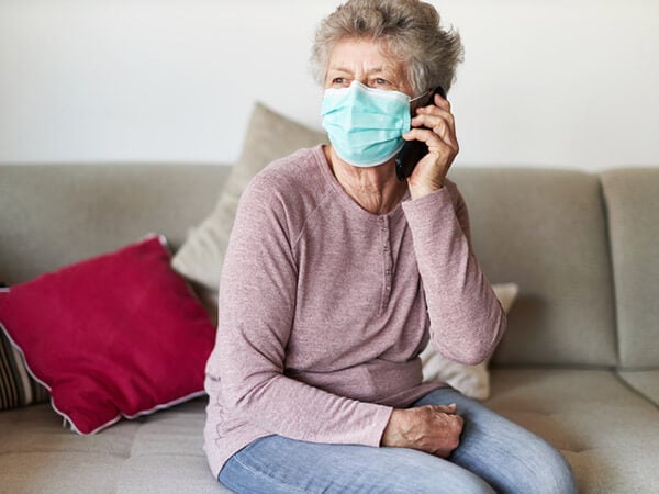 Older woman in mask using cell phone