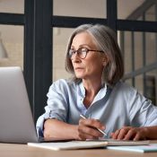Older woman looking at laptop and taking notes