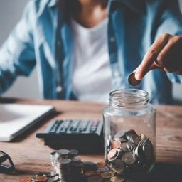 Young person saving coin in a jar