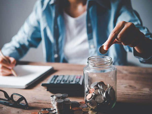 Young person saving coin in a jar