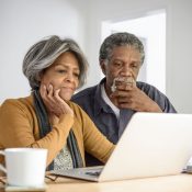Senior African American couple looking at a laptop, worried over retirement finances