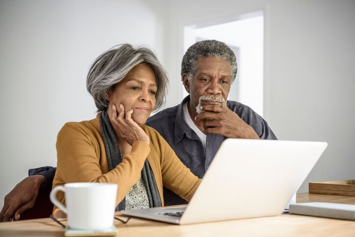 Senior African American couple looking at a laptop, worried over retirement finances