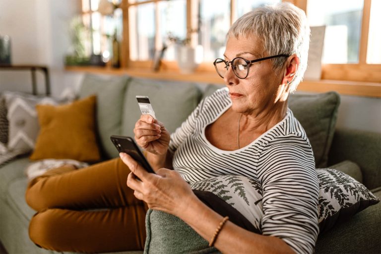 senior woman holding bank card and phone