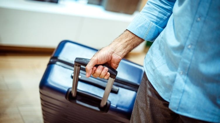 Man holding rolling suitcase