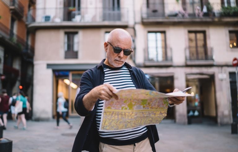 Senior man looking through map on city street